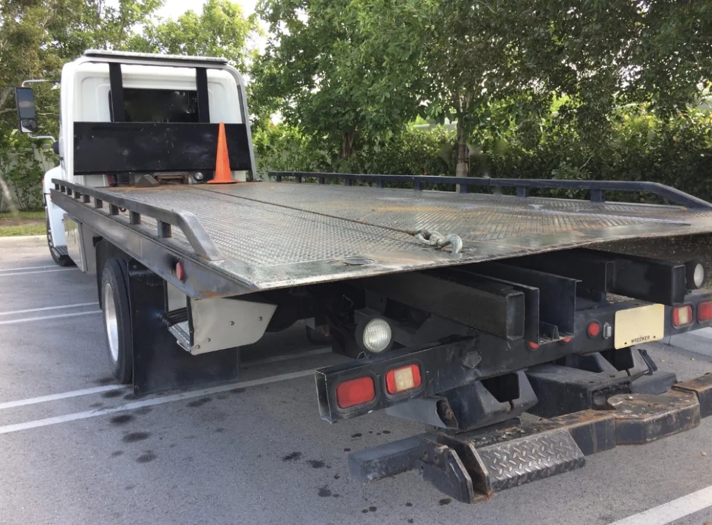 Commercial Towing 1 flatbed tow truck in parking lot parked near trees
